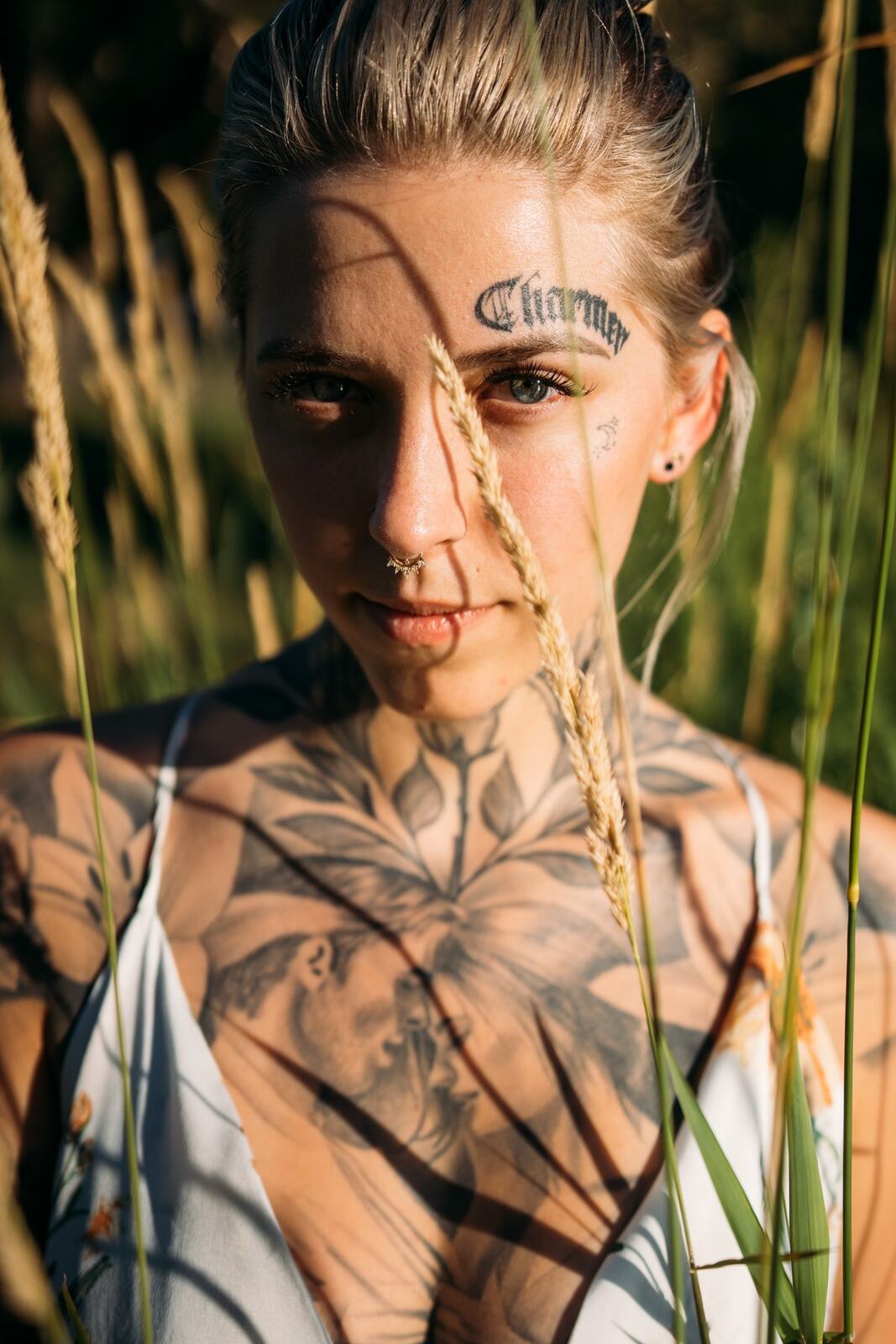 Rayleigh by Knox portraits story frame 7: Knox Mountain portraits in Kelowna with white floral dress, tattoo detail, reeds, water, sunlight and a stronger summer edge.