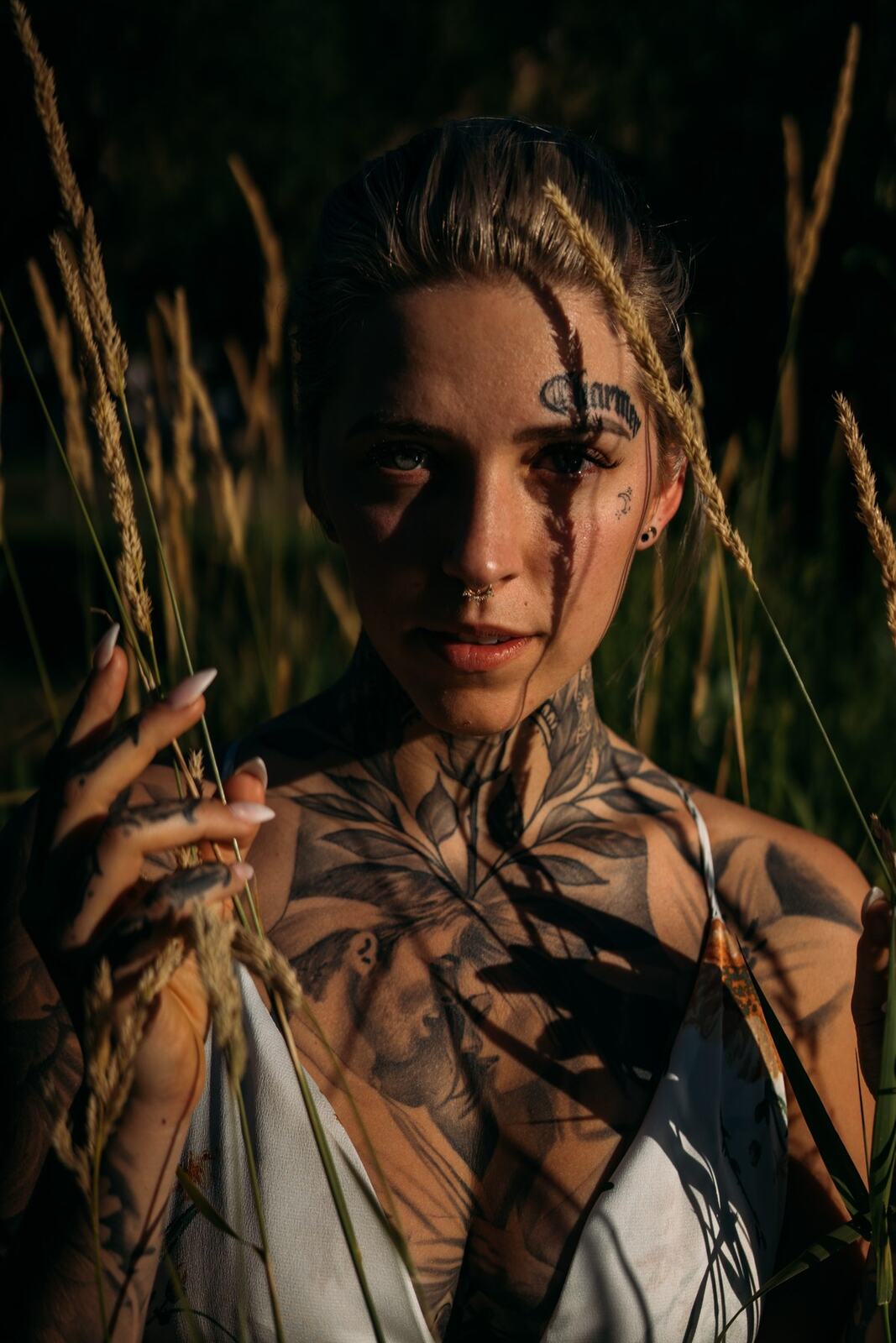 Rayleigh by Knox portraits story frame 8: Knox Mountain portraits in Kelowna with white floral dress, tattoo detail, reeds, water, sunlight and a stronger summer edge.