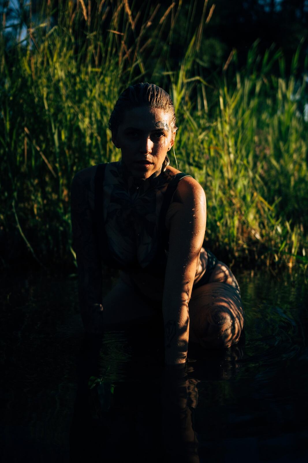 Rayleigh by Knox portraits story frame 12: Knox Mountain portraits in Kelowna with white floral dress, tattoo detail, reeds, water, sunlight and a stronger summer edge.