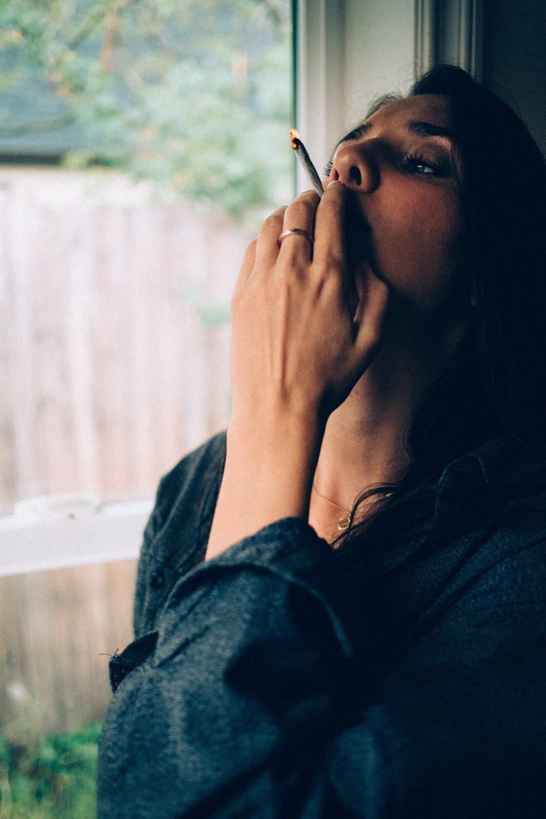 Rebecca in Smoke portraits story frame 15: A dark Kelowna portrait story for Rebecca with window light, smoke, denim, close expression and a low-key editorial mood.