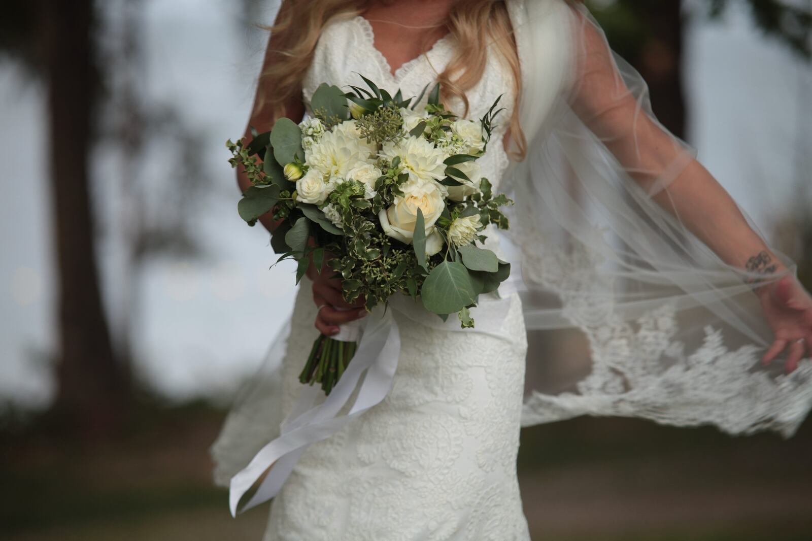 Sarah's bouquet and wedding dress beside the water