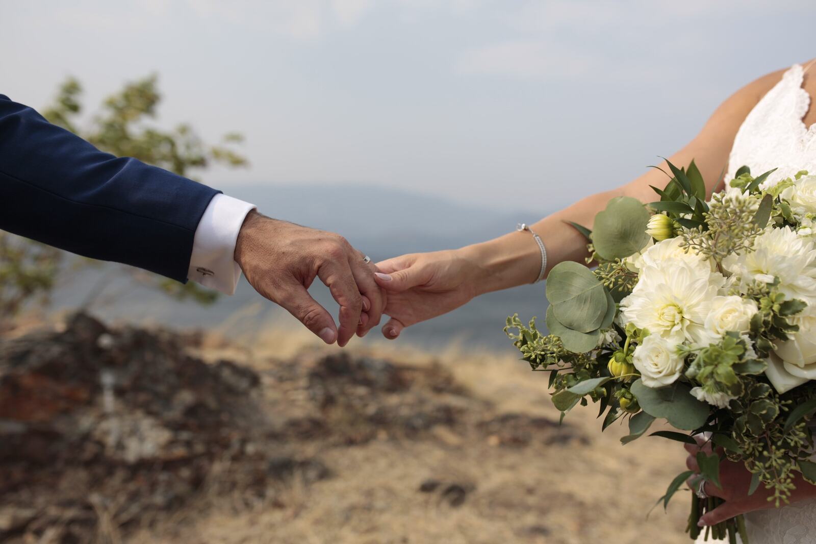 Sarah and Greg holding hands with the bouquet between them