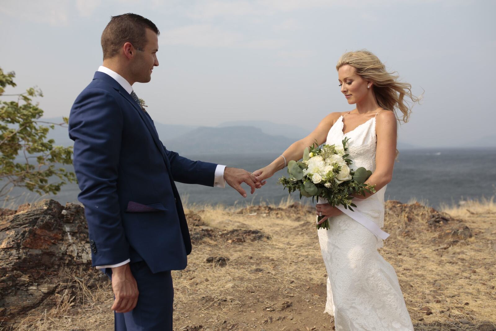 Sarah and Greg holding hands in the lakeside landscape