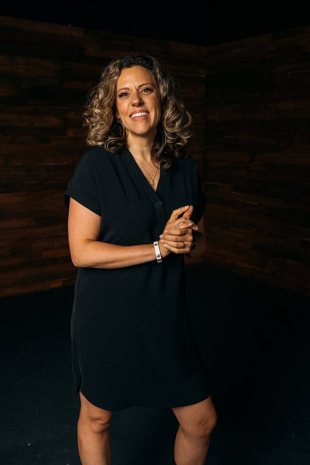 Trisha Miltimore corporate story frame 18: Personal-brand portraits for Trisha Miltimore in Kelowna, moving from clean business profile images into darker wood-wall portraits with black wardrobe and confident brand range..