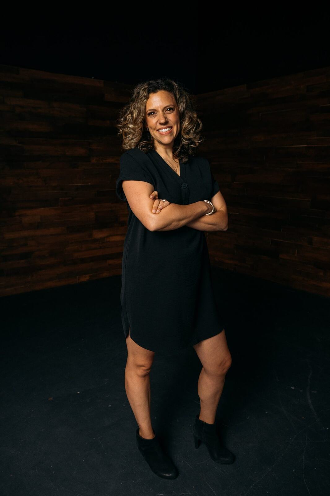 Trisha Miltimore corporate story frame 20: Personal-brand portraits for Trisha Miltimore in Kelowna, moving from clean business profile images into darker wood-wall portraits with black wardrobe and confident brand range..